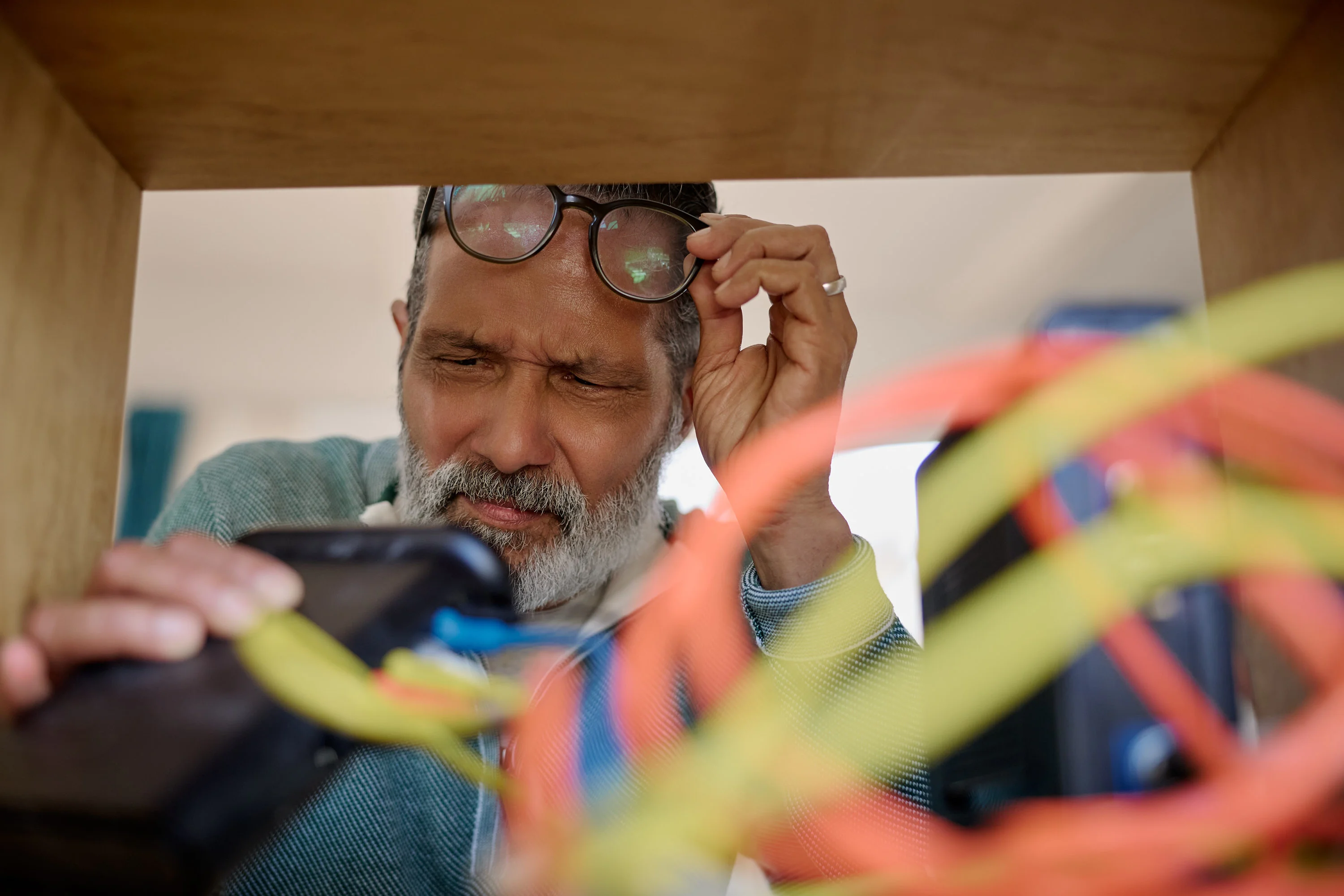 Anthony lifting his glasses while inspecting the router inside a cabinet