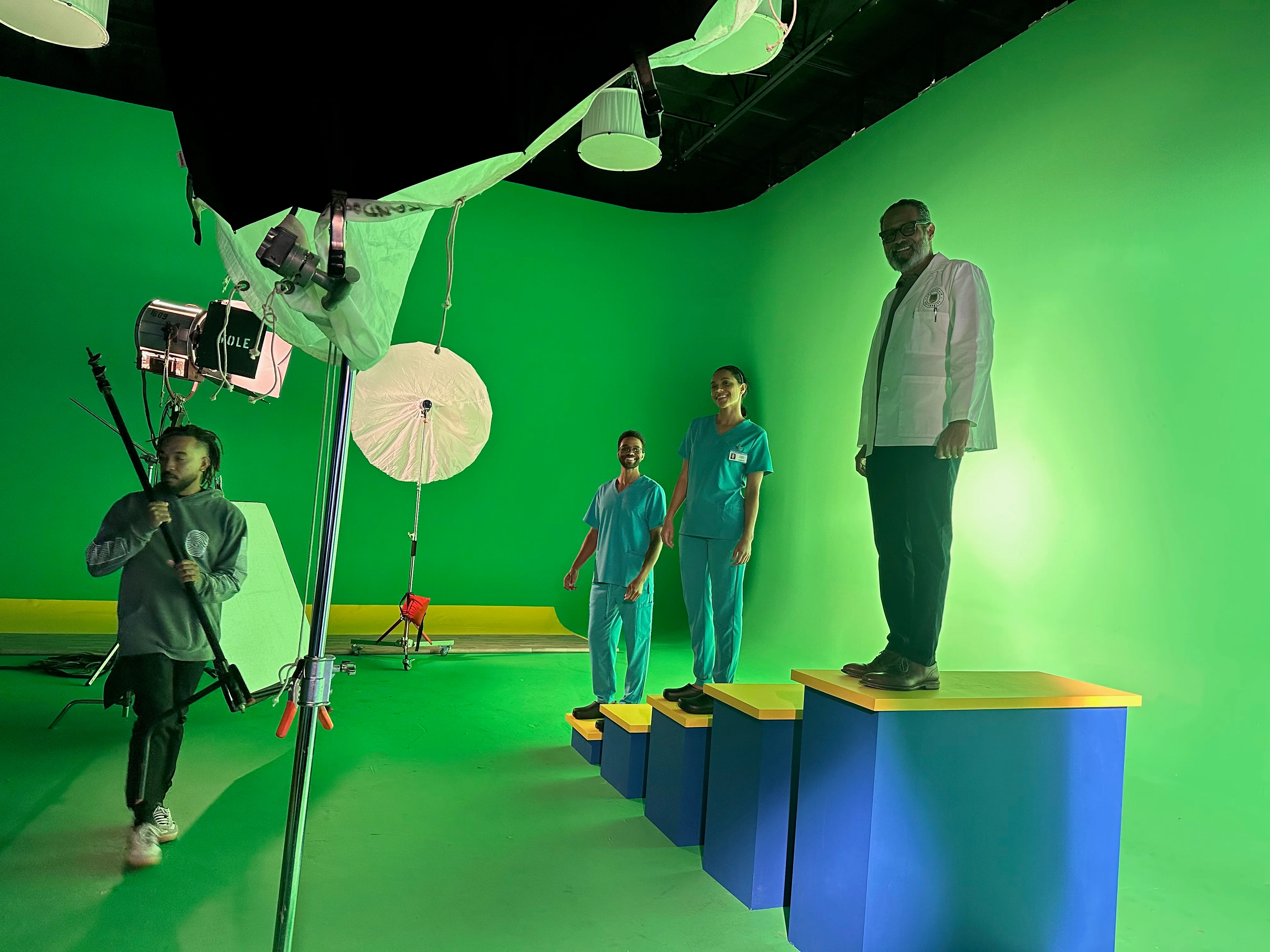 Wide production view of Anthony on the tallest platform, with performers, crew, and studio lighting