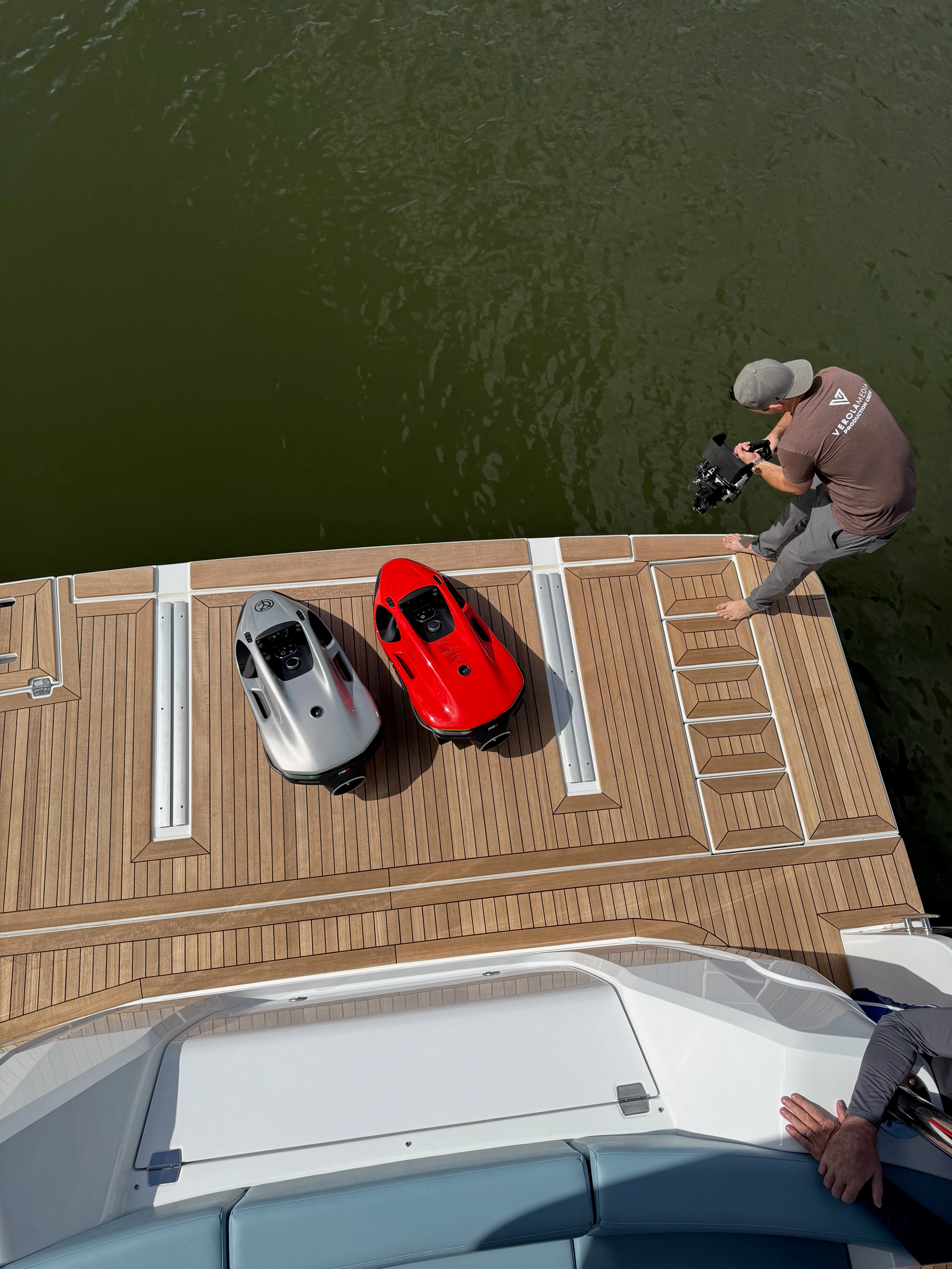 Overhead view of a camera operator actively filming from the Cruisers Yachts 50 FLY swim platform