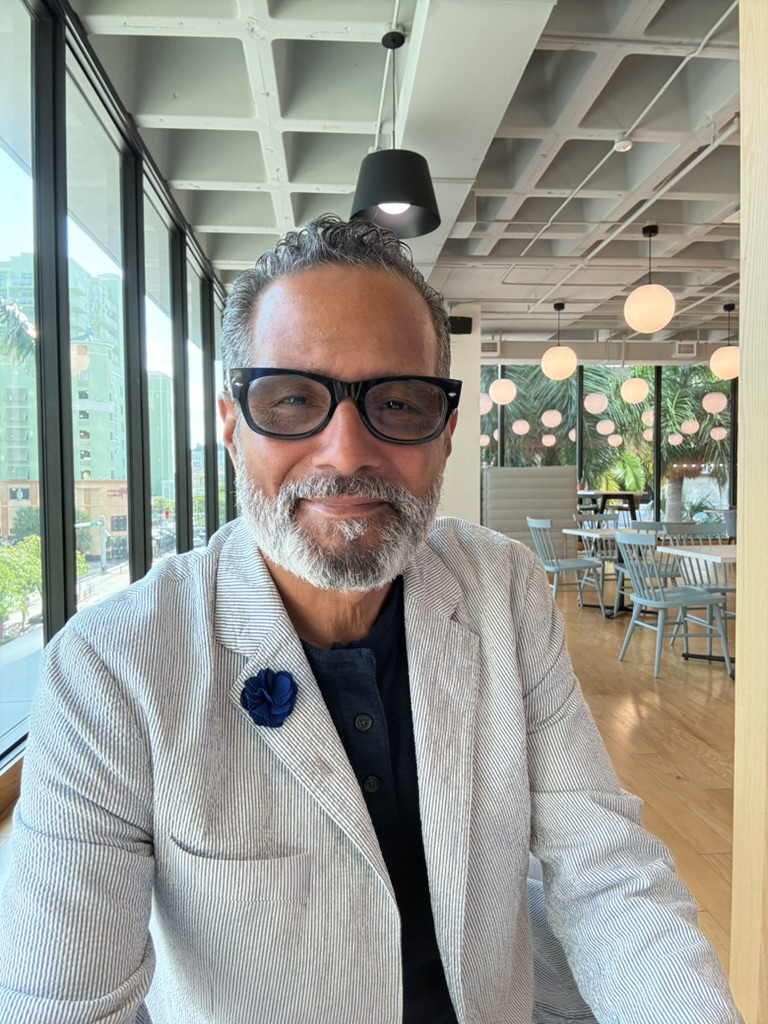 Anthony Rolón seated beside the windows in a café